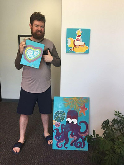 Bo with Bo's Creation Station showing off three of his art cartoon prints.