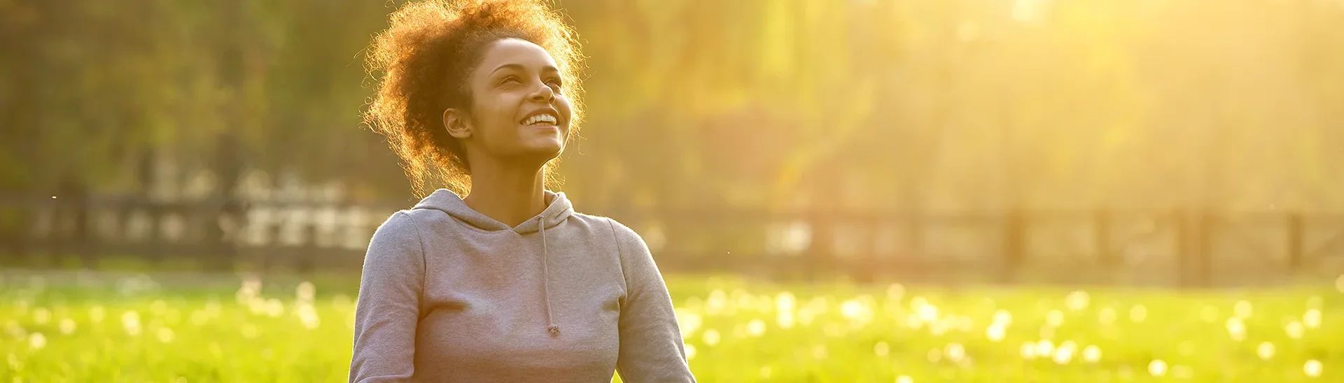 Young African-American woman sitting in a field with the sun glowing