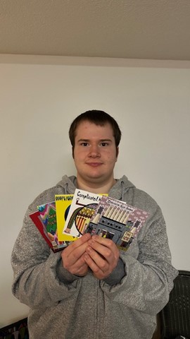 Jacob Ray holding several of his greeting cards an bookmarks from Complication Music Machine.