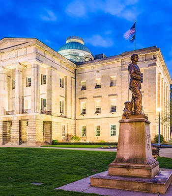 North-Carolina-Capital North Carolina state capital building and statue out front in early evening.