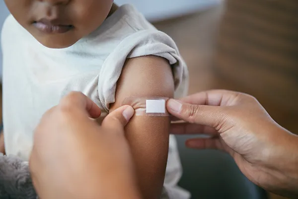Child-Getting-Bandaid-Put-On_2293728981 A young child having a band aid put on their arm after what may have been receiving a shot for a vaccination.