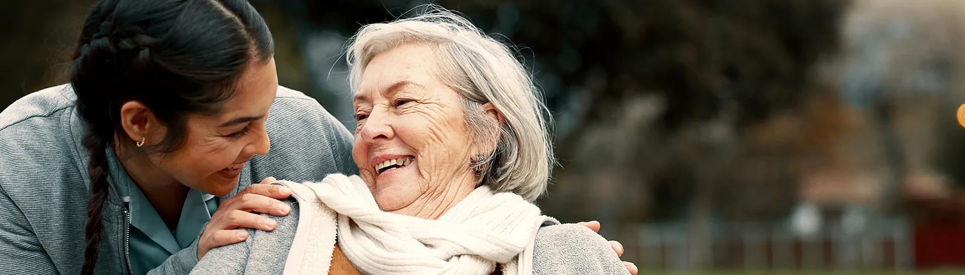 Elderly woman sharing a smile with a younger healthcare assistant.