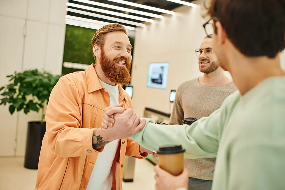 Three guys smiling and shaking hands at work.