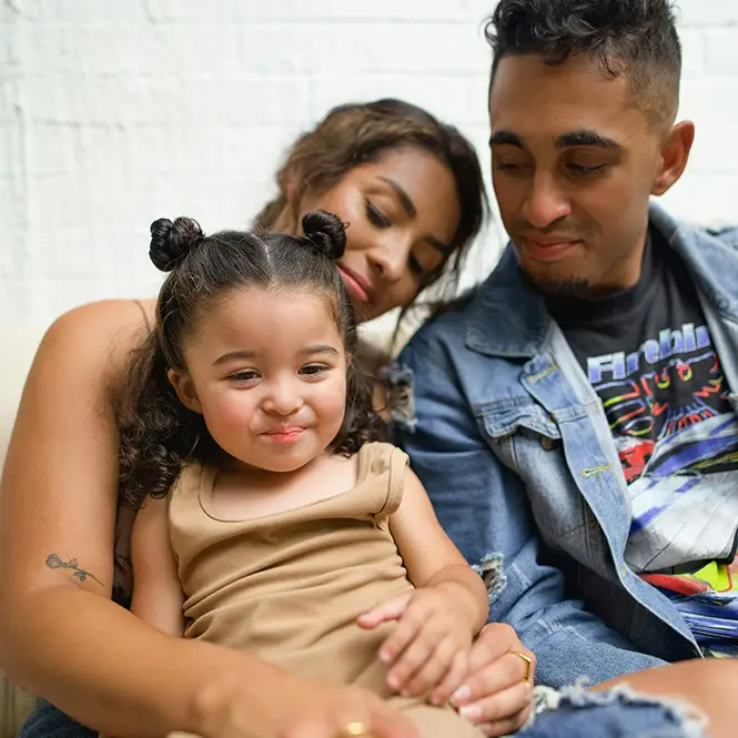 A family sitting and smiling while they wait at an office.